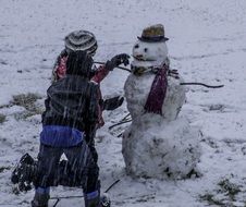 dirty snowman and kids playing in winter