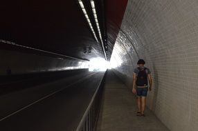 walking person in dark tunnel track