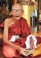 elderly buddhist monk sits in temple, myanmar, yangon