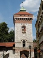 medieval gate tower in city wall at blue sky background with white clouds, poland, krakow