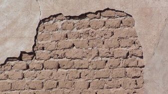 damaged stucco on a brick wall