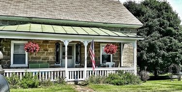 old stone house with american flag on porch