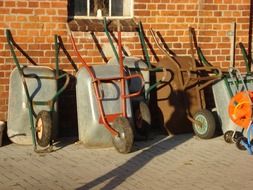 Wheelbarrows stand near a brick building
