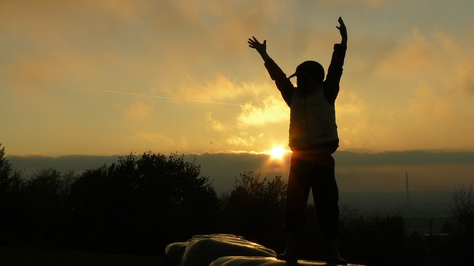 silhouette of a boy in the colorful setting sun above the landscape
