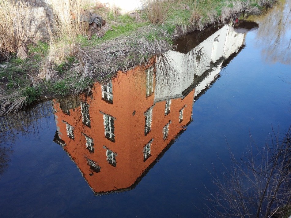 mirror reflection of a house with orange walls in the water