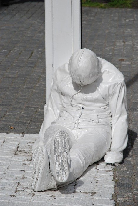 reclining man like a white statue in the middle of the street