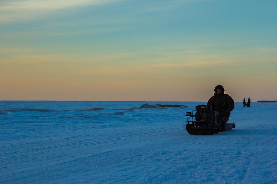 man rides through the snow on a snowmobile