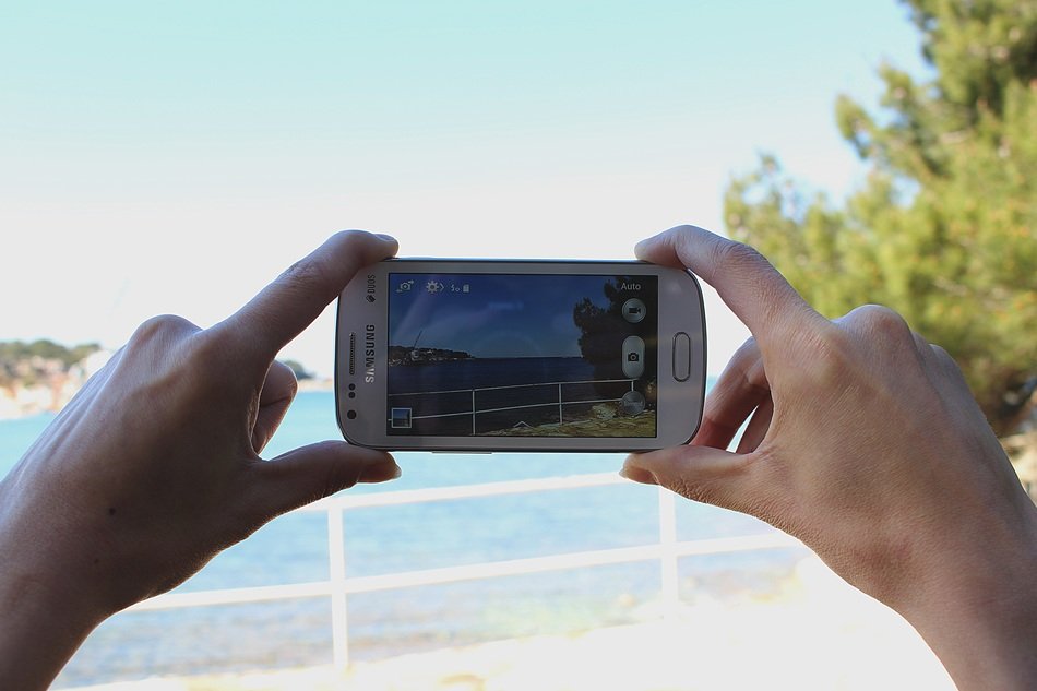 the man takes the picture of a landscape on a Samsung