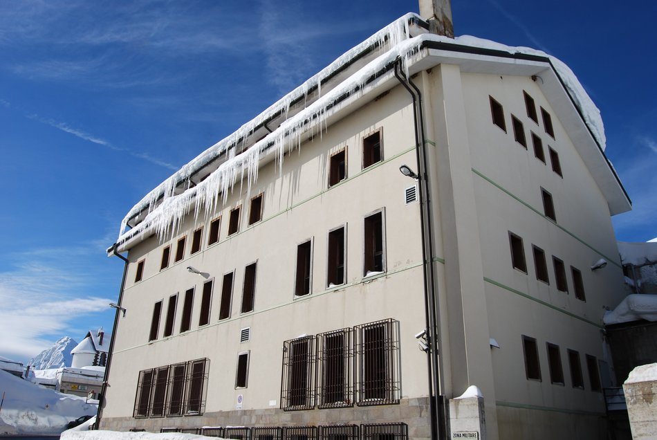 snow and icicles on roof of white building, italy