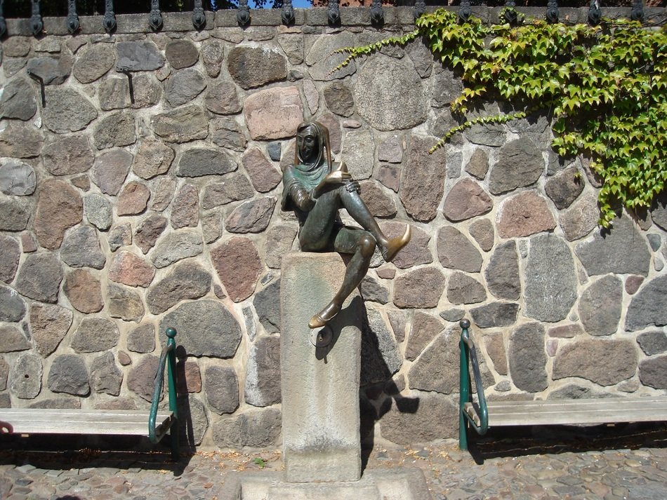 till eulenspiegel bronze statue at pile before brick wall, germany, mÃ¶lln