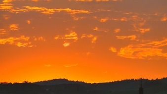 sunset with orange clouds over dark silhouettes