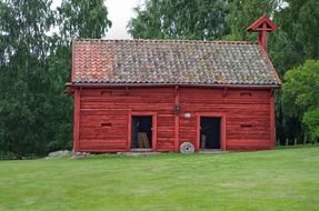 landscape of old red wooden barn at summer forest in sweden
