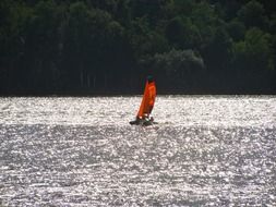 red catamaran sailing on glossy water, czech, brno Reservoir