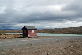 Little house by the lake on beautiful landscape with hills in Iceland