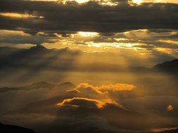 the golden rays of the sun illuminate the dark clouds