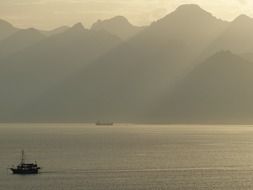 Landscape with the beautiful mountains and boats on the water in colorful sunset