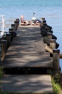 two young men lay on boardwalk at water