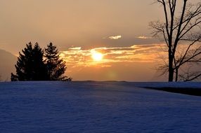 rising sun in the clouds over a winter landscape