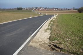 asphalt road between green fields