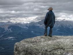 child boy standing on rock in view of scenic mountains, canada