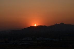 glow of orange sunset due to mountains