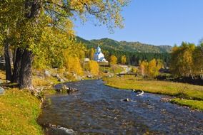 distant view of the church near the river in autumn