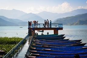 row of boats at pier on lake fewa in scenic landscape, nepal, pokhara