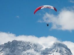 Skydiver with colorful parachute over the beautiful mountain of Valais in snow in Switzerland