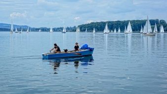 two man in rowing boat on chiemsee lake in view of sailing boats, germany