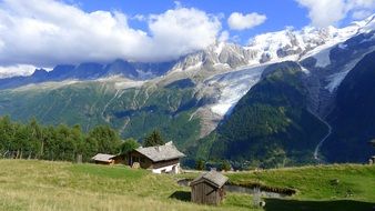 hut, pond and barn amid majestic mountains