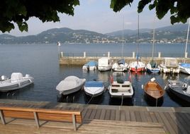 boats on the pier in the background of the mountains in Italy