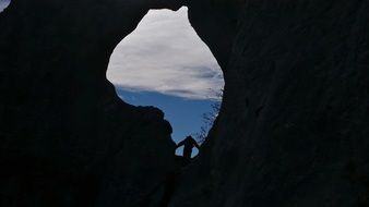 person silhouette in rock opening