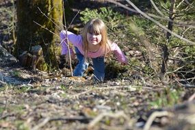 small blonde girl walking in forest