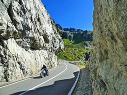 motorcycle on road among rocks at summer sunny day, switzerland
