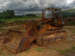 Rusty excavator in the forest in stormy weather