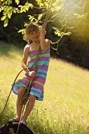 Little girl on a swing in the rays of sunlight