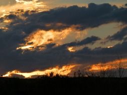 The setting sun behind dark clouds