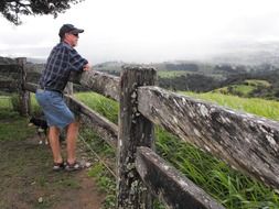 man is leaning on a wooden fence in rural Australia