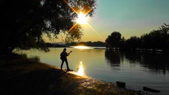 Guitar player near the river at dusk