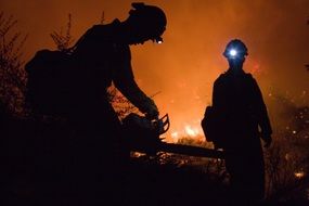 fire fighters with chain saw at night