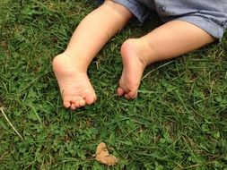The legs of a young child on green grass