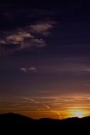 orange sun behind dark mountain