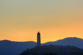 scenic sunset with red sky and pagoda on hill