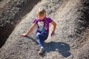 child girl climbing down sand hill