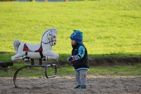 child in the park with a toy horse