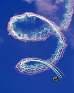 rainbow spiral from skydiver on blue sky