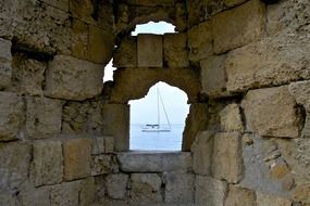 Stone wall with water view with the ship in Greece in summer