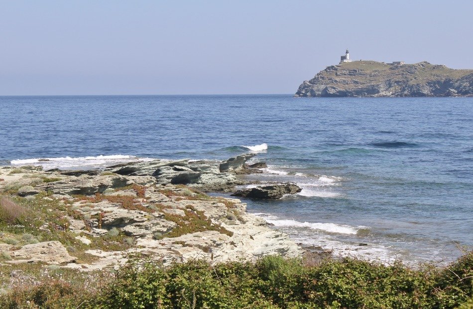 wild corsican seacoast and distant lighthouse on cliff