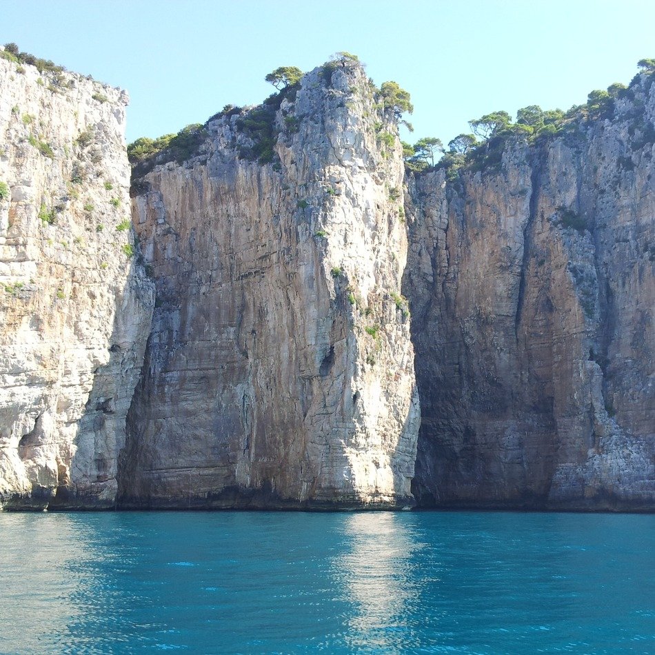 Beautiful Montagna Spaccata mountain with plants near the blue water