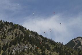 parachutists in the sky near mountains